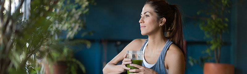 Woman peacefully drinking green smoothie after practicing yoga.